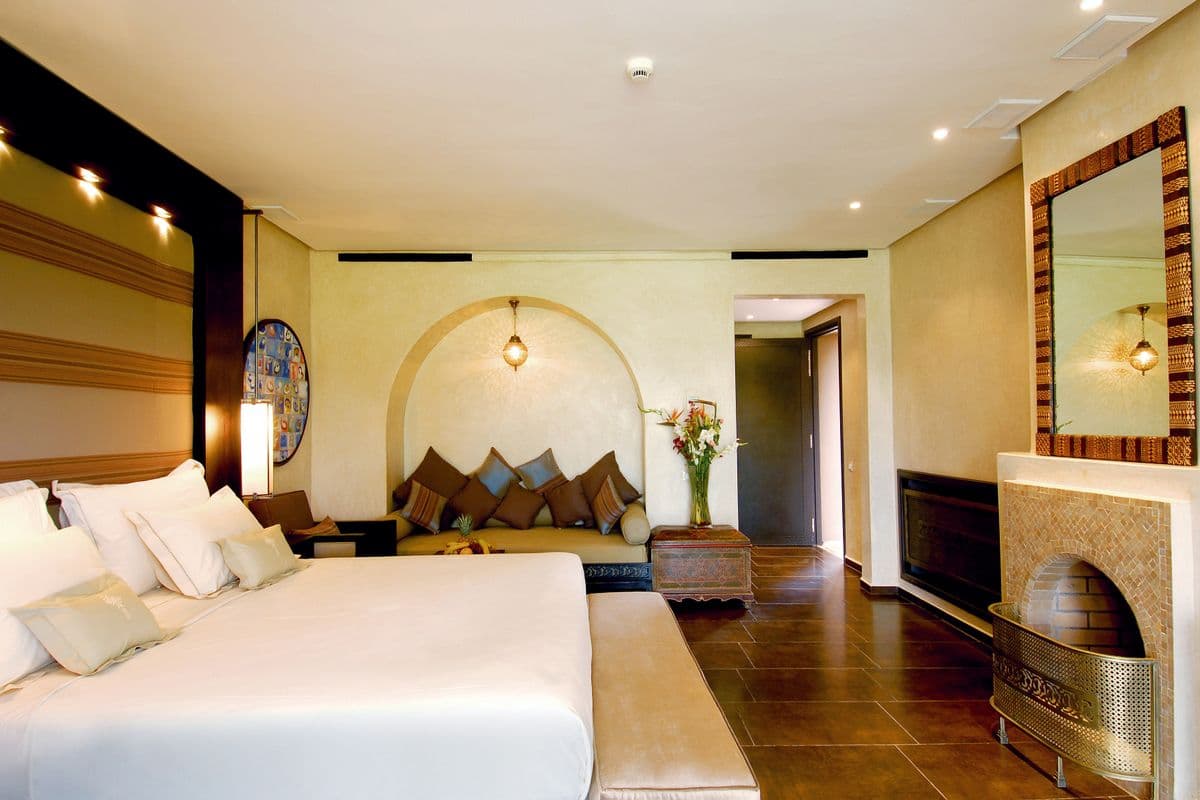 A hotel room with a large bed, warm lighting and a seating area